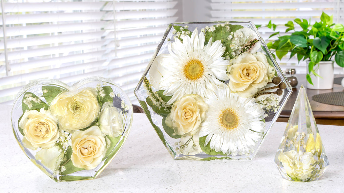 Resin flower keepsakes made by Everlasting Bloom Co. including hexagon, heart, and ring holder designs displayed on a countertop.