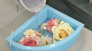 Artist pouring PetalSafe resin into a floral mold to preserve wedding flowers