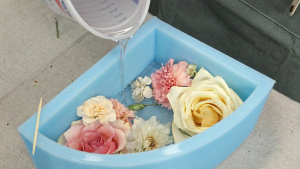 Artist pouring PetalSafe resin into a floral mold to preserve wedding flowers