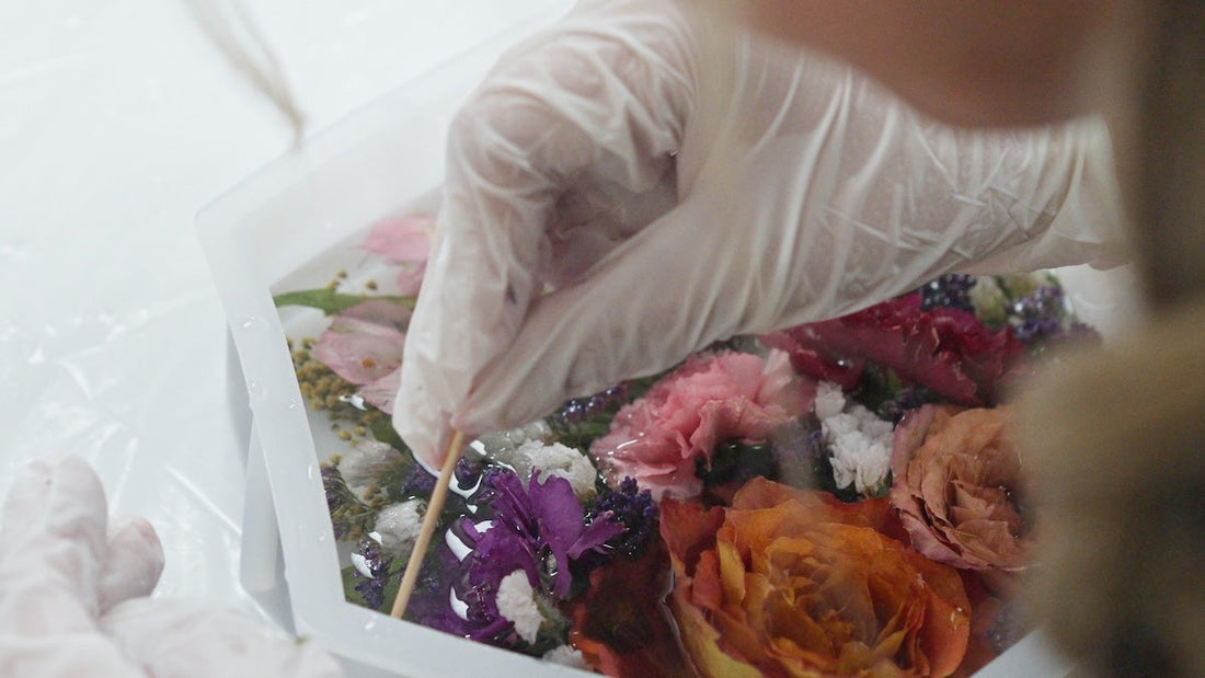 Over-the-shoulder view of wedding flowers being carefully arranged into a resin mold for preservation at Everlasting Bloom Co.