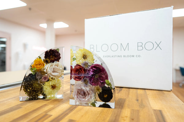 Two resin bookend keepsakes with preserved wedding flowers displayed in front of a Bloom Box shipping kit from Everlasting Bloom Co.