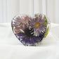 Heart-shaped resin block featuring preserved purple and lavender wedding flowers with soft greenery, arranged in a clear handcrafted display — floral preservation by Everlasting Bloom Co.