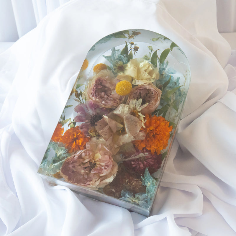 Large arch-shaped resin block featuring preserved roses, marigolds, and mixed colorful wedding flowers, arranged in a handcrafted clear display — floral preservation by Everlasting Bloom Co.