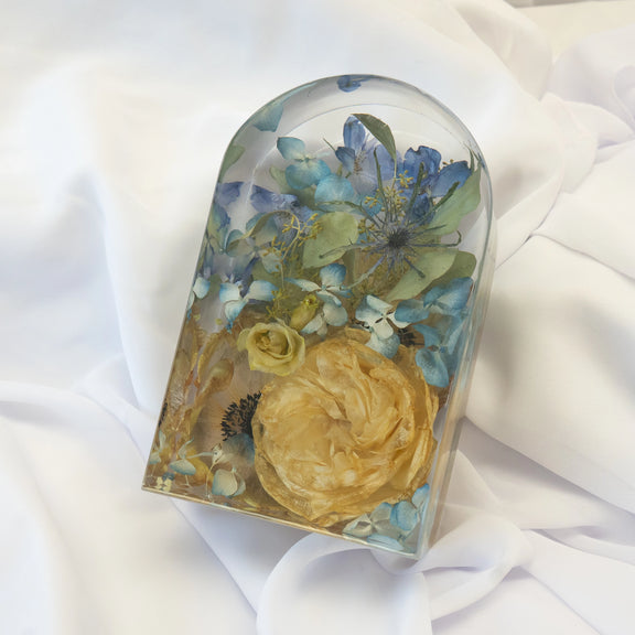 Small arch-shaped resin block featuring preserved yellow roses and blue hydrangeas, arranged in a clear handcrafted display — wedding flower preservation by Everlasting Bloom Co.