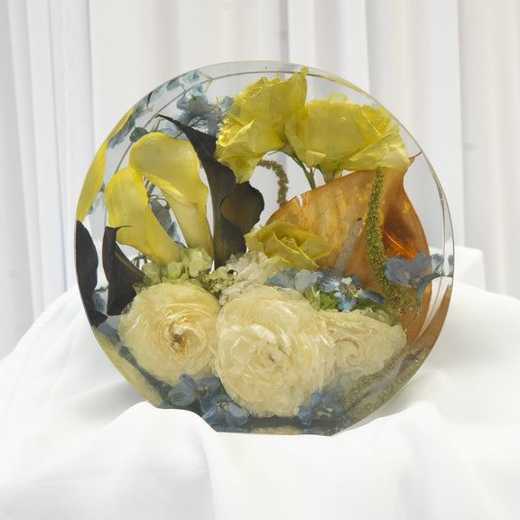 Standing round resin display featuring preserved yellow roses, cream blooms, and soft blue florals arranged in a clear sculptural design — handcrafted flower preservation by Everlasting Bloom Co.