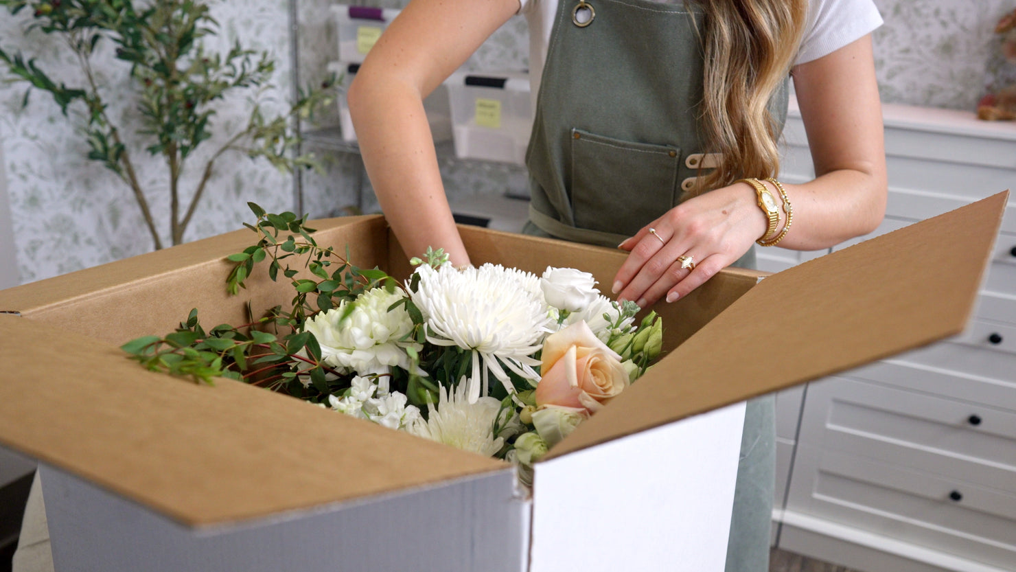 Packing a fresh wedding bouquet with roses and chrysanthemums into a Bloom Box for safe shipping to Everlasting Bloom Co.