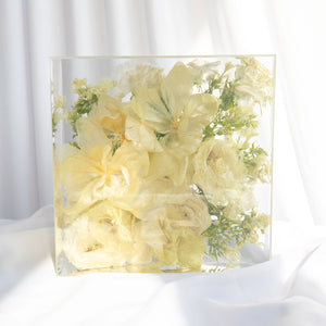Square resin floral block with preserved ivory lilies, cream garden roses, and white stock from a wedding bouquet