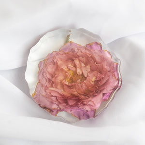 Scalloped-edge coaster with a single dusty pink garden rose from a wedding bouquet