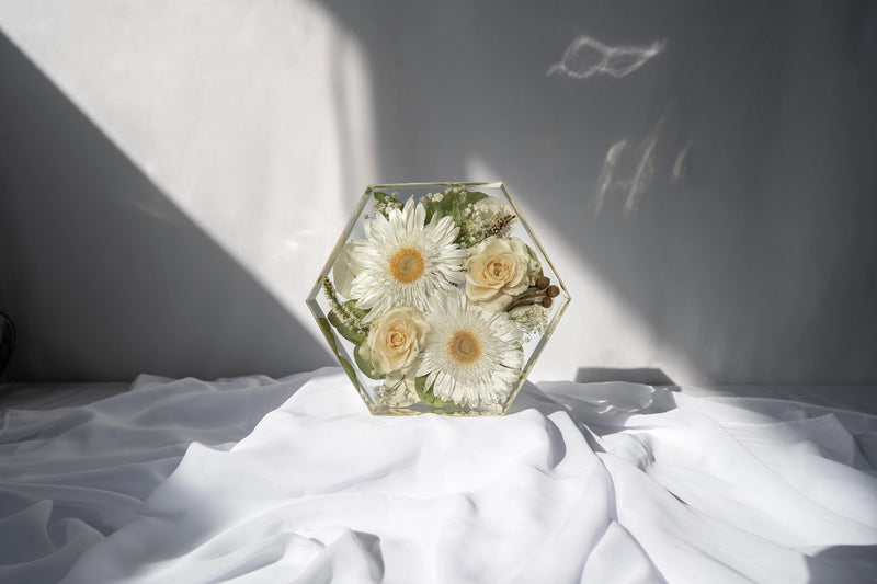 Front-facing view of hexagon resin mold filled with dried flowers from a wedding bouquet.