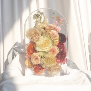 Large arch with ivory and blush garden roses, coral roses, burgundy ranunculus, a white anemone, white snapdragons, and pink larkspur from a wedding bouquet