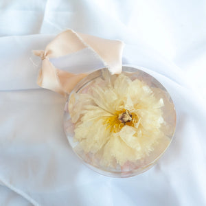 Round resin ornament with peach silk ribbon, preserved ivory peony from a wedding bouquet