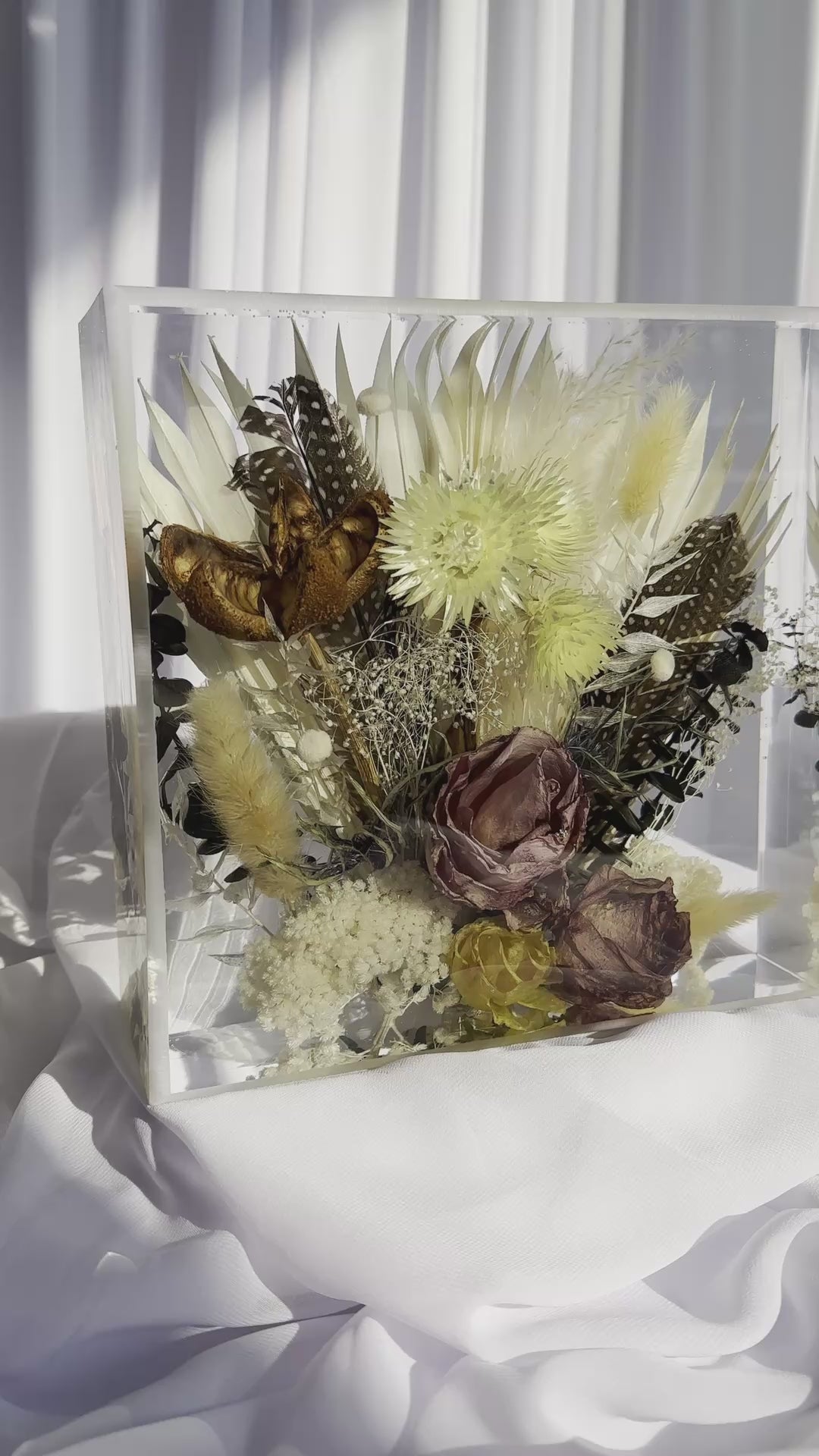 Panning video of an 8x8 resin flower preservation block featuring dried florals, pampas grass, preserved mauve rose, yellow strawflowers, feathers, and a butterfly — handmade memorial or wedding keepsake in clear epoxy