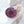 Handmade round resin ornament with a preserved purple gerbera daisy, finished with a cream silk ribbon bow, displayed on white fabric