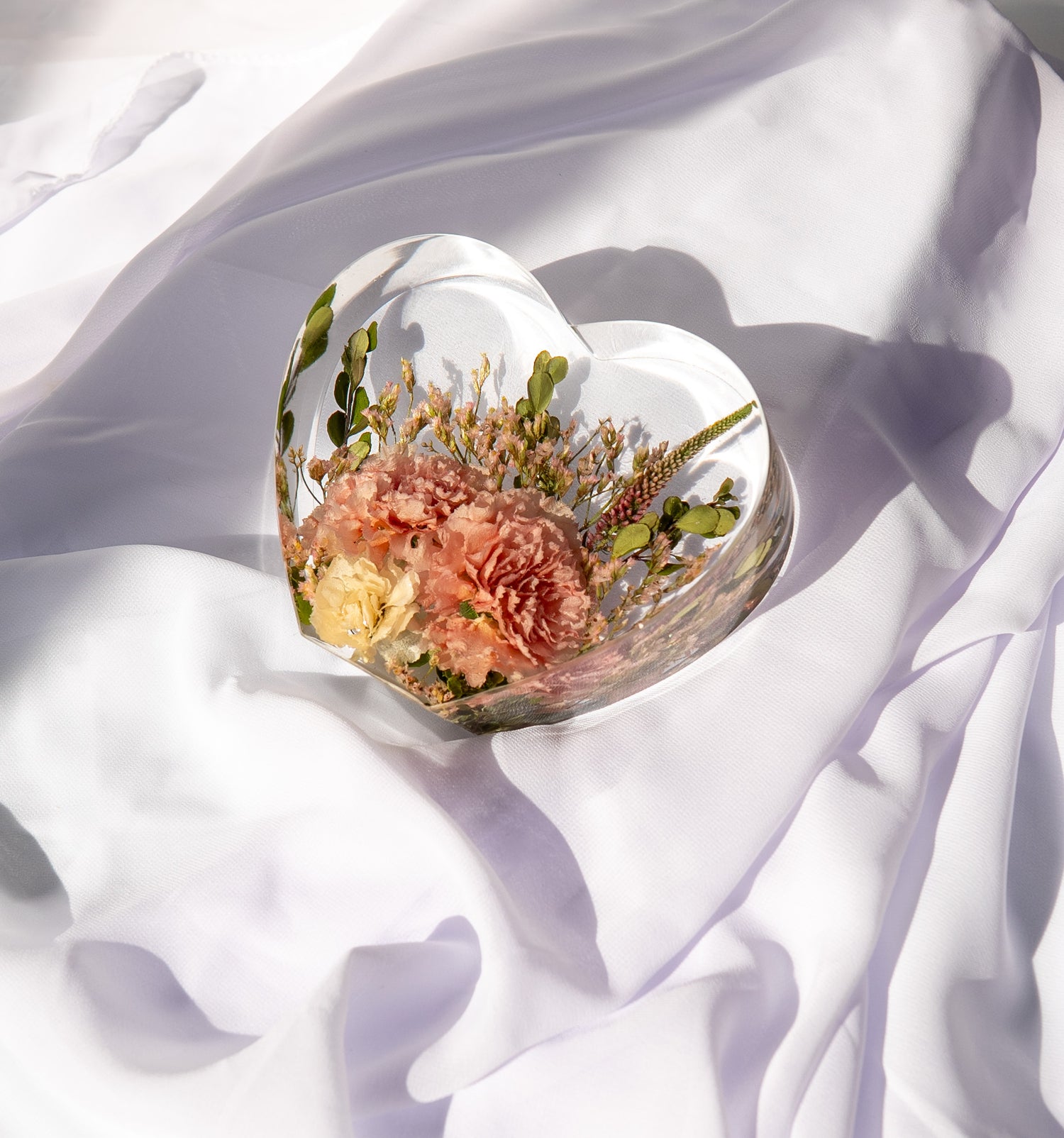 Heart-shaped resin keepsake showcasing real wedding flowers preserved in crystal-clear epoxy.