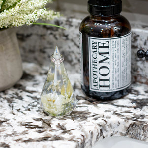 Resin flower ring holder displayed beside a sink with a diamond engagement ring.