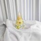 Resin ring holder with preserved yellow flower and delicate greenery, displayed on soft white fabric backdrop