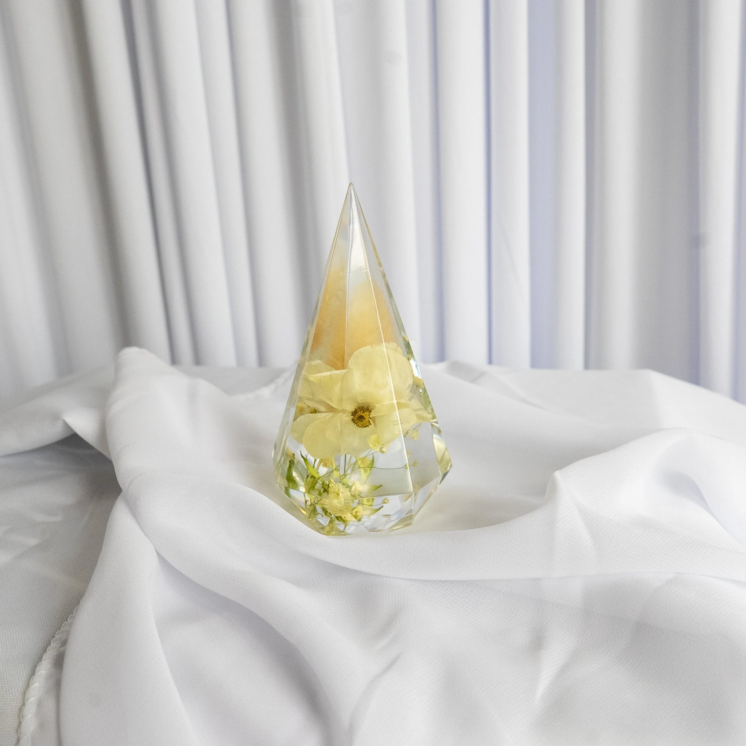 Resin ring holder with preserved yellow flower and delicate greenery, displayed on soft white fabric backdrop