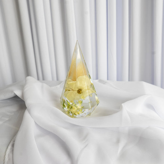 Resin ring holder with preserved yellow flower and delicate greenery, displayed on soft white fabric backdrop
