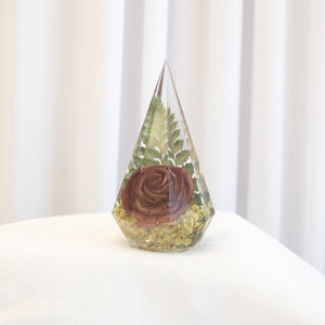 Faceted pyramid resin ring holder with preserved rust rose, green fern, and yellow baby's breath from a wedding bouquet