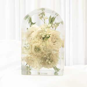 Small arch-shaped resin keepsake with preserved white roses, scabiosa, baby's breath, and greenery from a wedding bouquet
