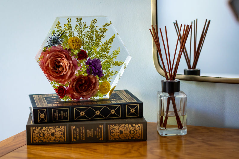 Bright, colorful floral resin keepsake in a hexagon shape styled on a dresser.
