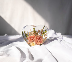 Small resin heart mold filled with dried bouquet flowers for lasting floral preservation.