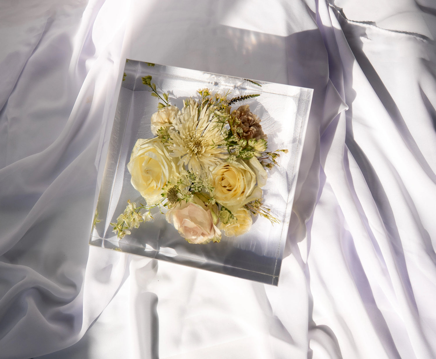 Top-down view of a square resin block showcasing vibrant preserved bouquet flowers.